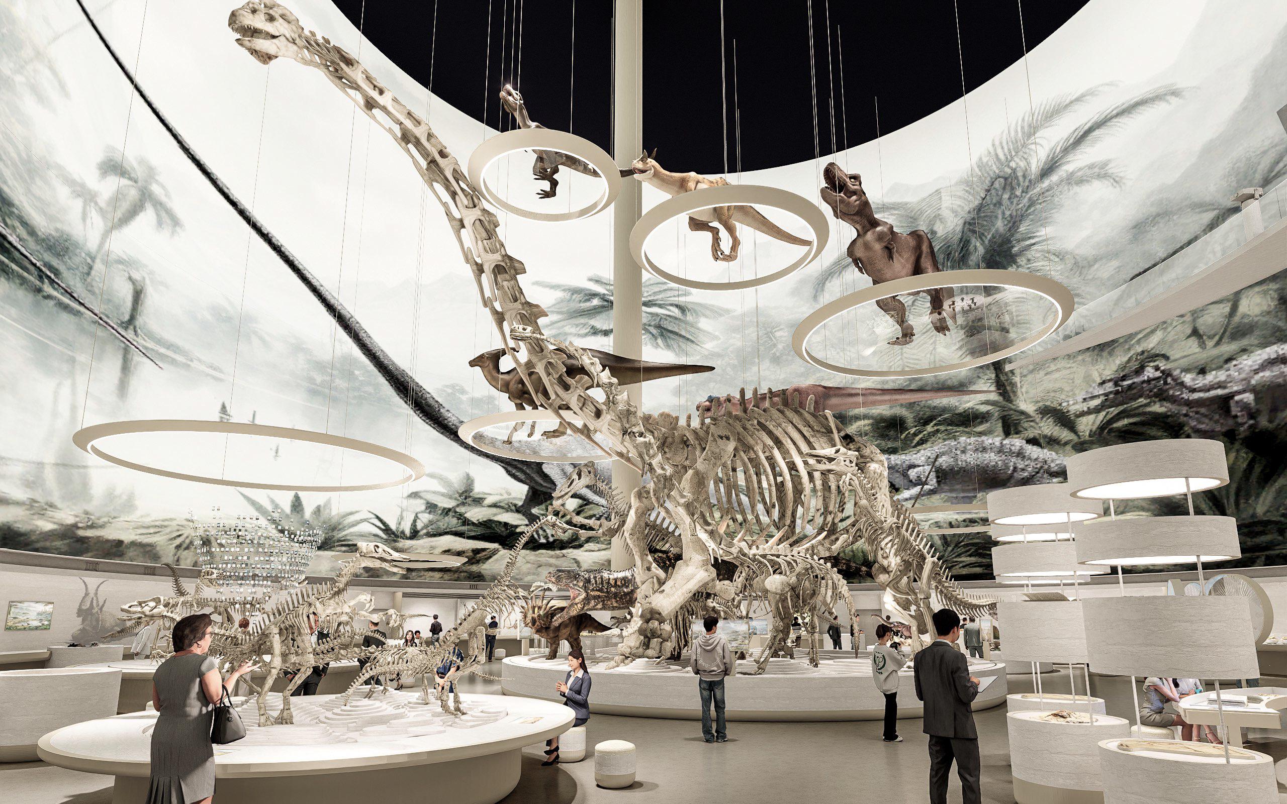 Große, helle Museumshalle mit zentralem Dinosaurierskelett, umgeben von weiteren Fossilien, hängenden Modellen und Besuchern.