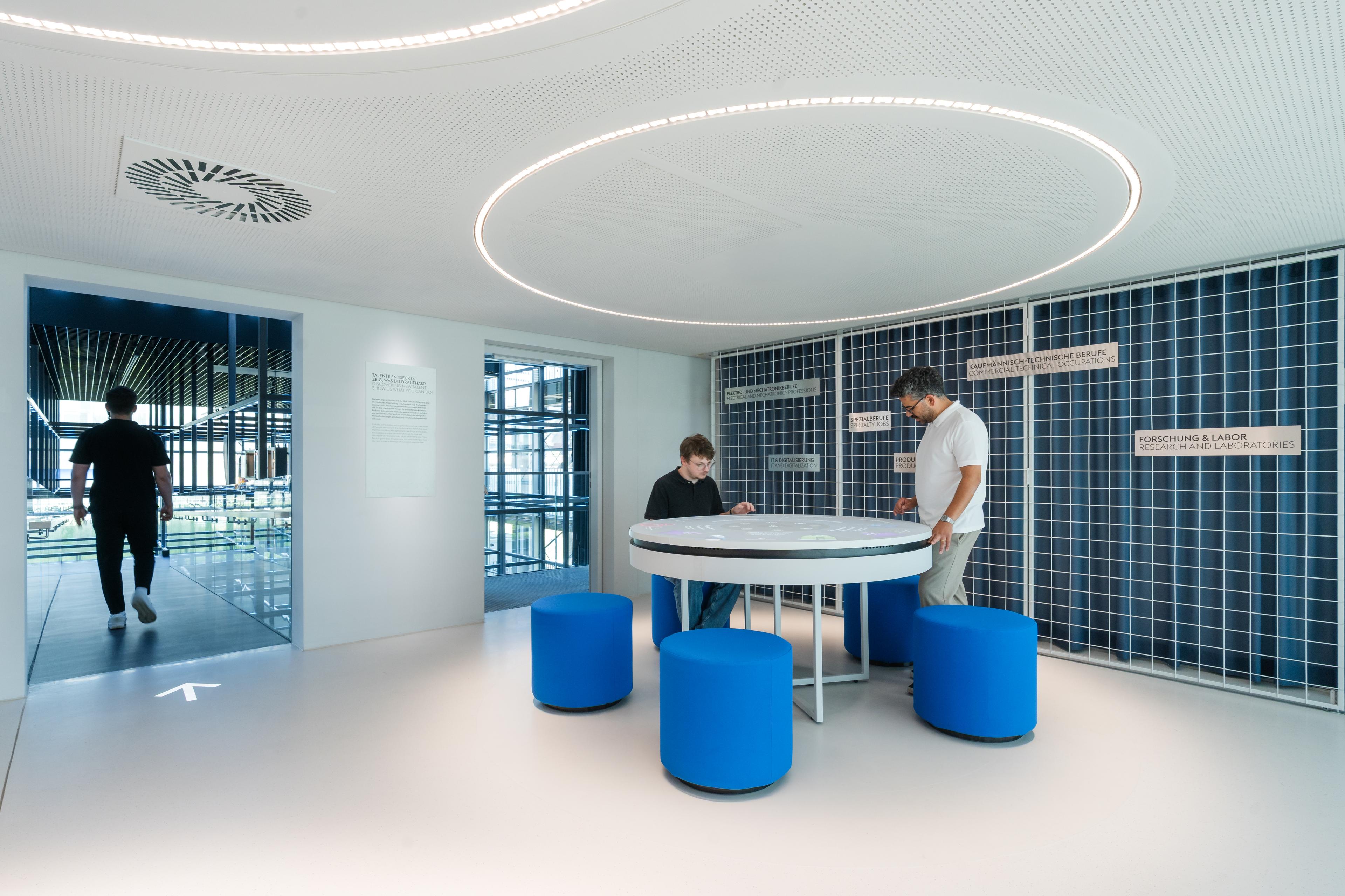 Visitors explore an interactive table exhibit that highlights the diversity of professions, skills, and career opportunities within voestalpine