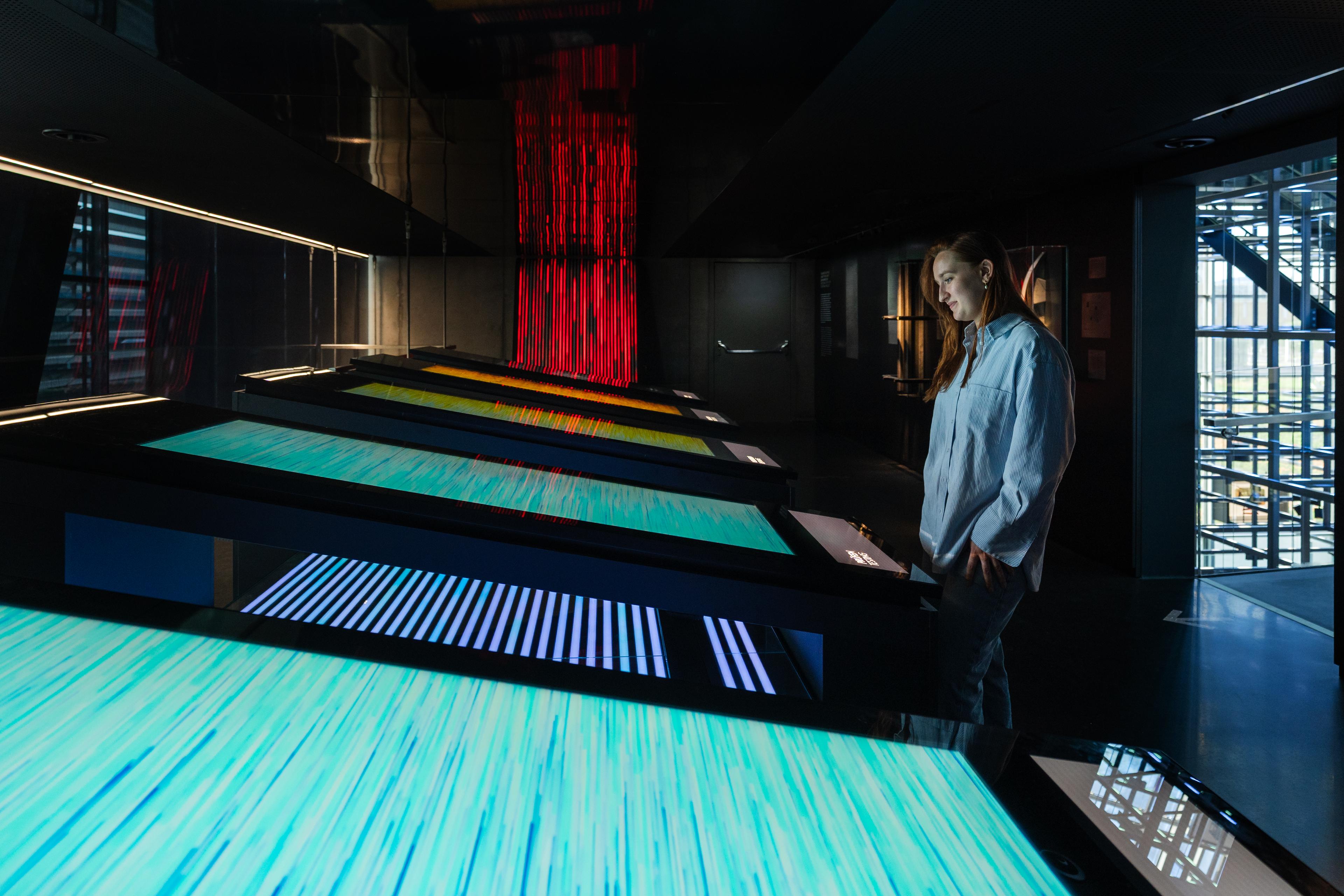 Visitor explores interactive media tables that explain steel production processes through animated data visualizations and immersive digital storytelling