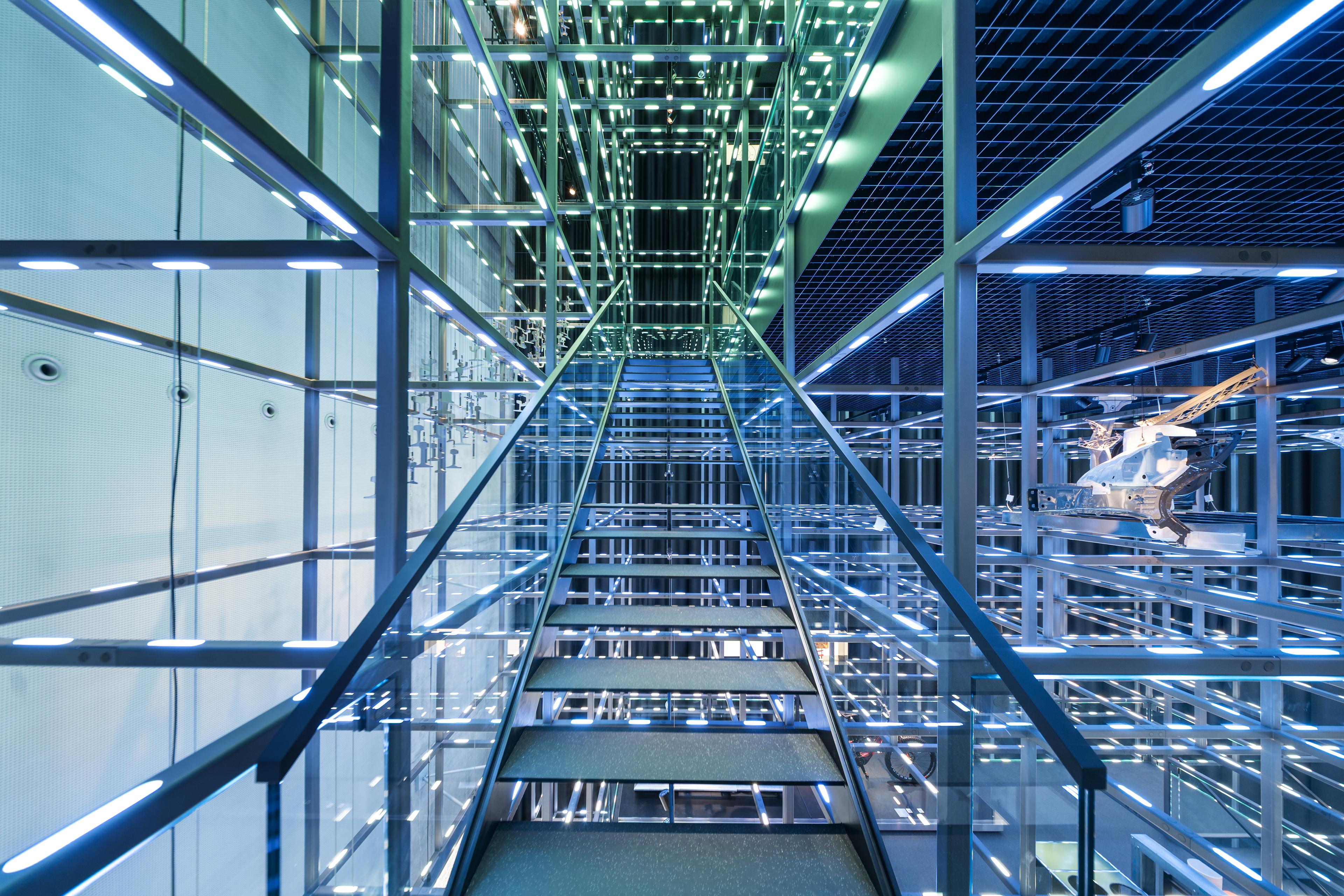 Stairways and walkways weave through the illuminated Grid, a suspended steel structure that forms the central architectural and exhibition framework of the voestalpine Stahlwelt